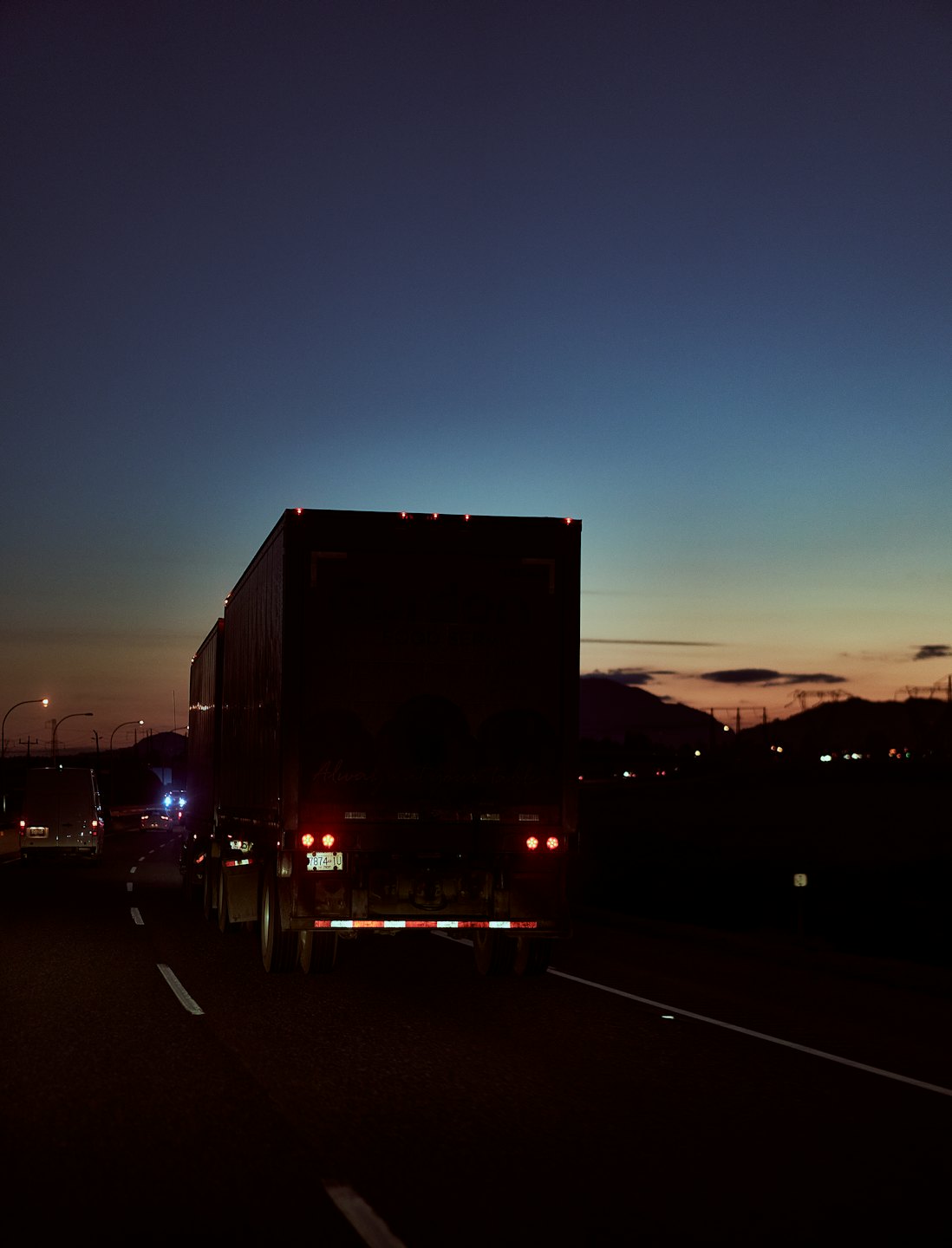 Ciężarówka z naczepą jadąca autostradą o zmierzchu.